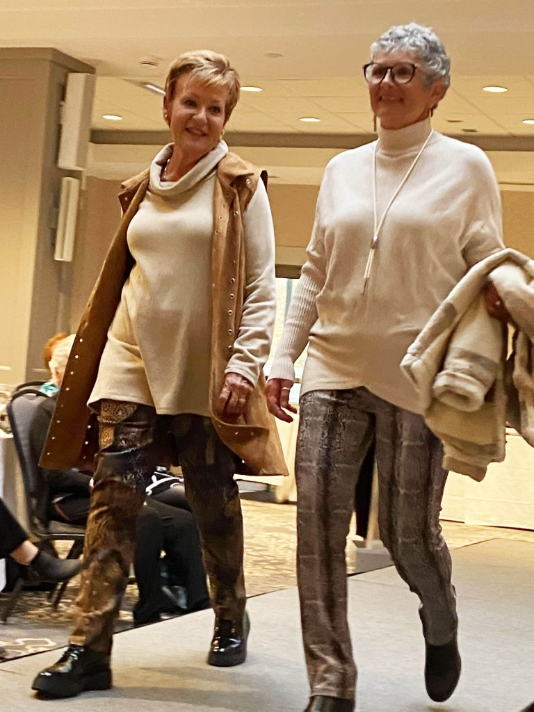 2 ladies in beign tops and brown pants, neck accents