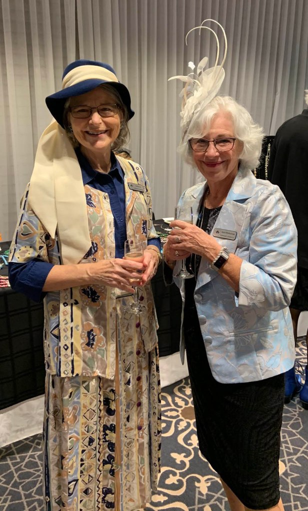 2 ladies in fascinator hats at the tea party. One with upswept feathers.