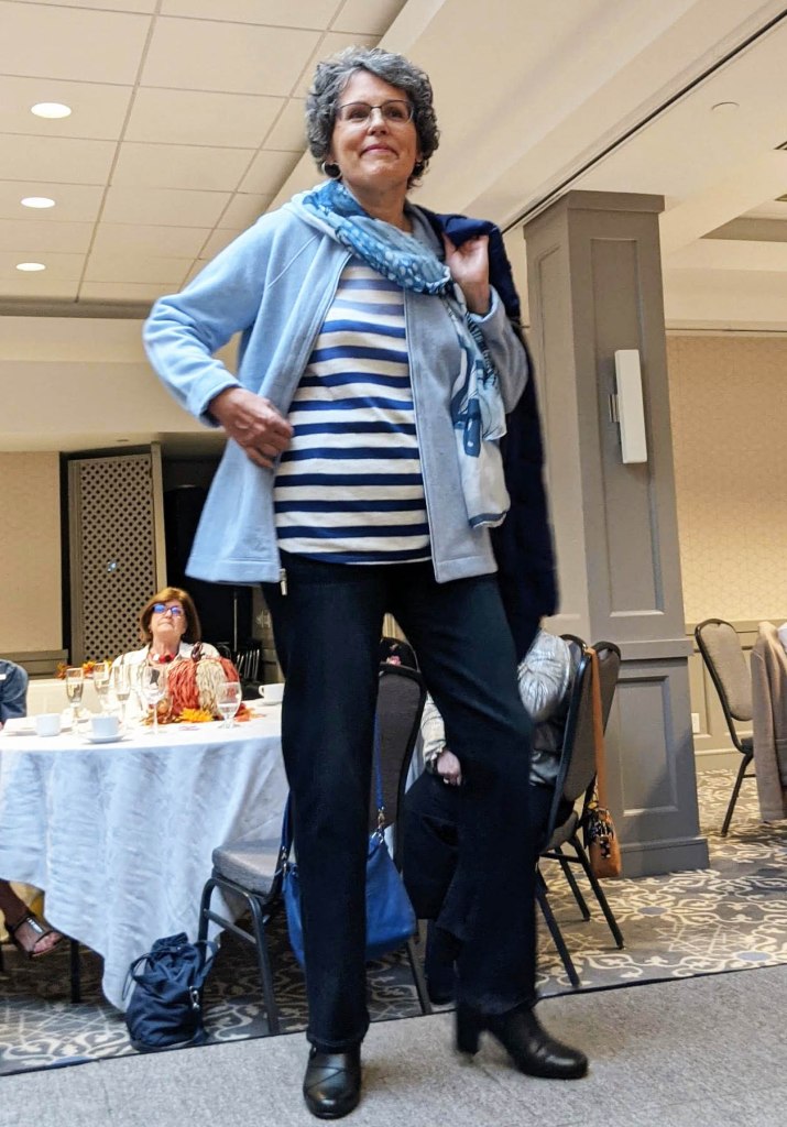 Lady in blue jacket with striped top and dark pants, accent scarf in blue