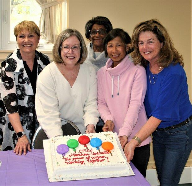 5 women with a cake reading "The Power of women working together"