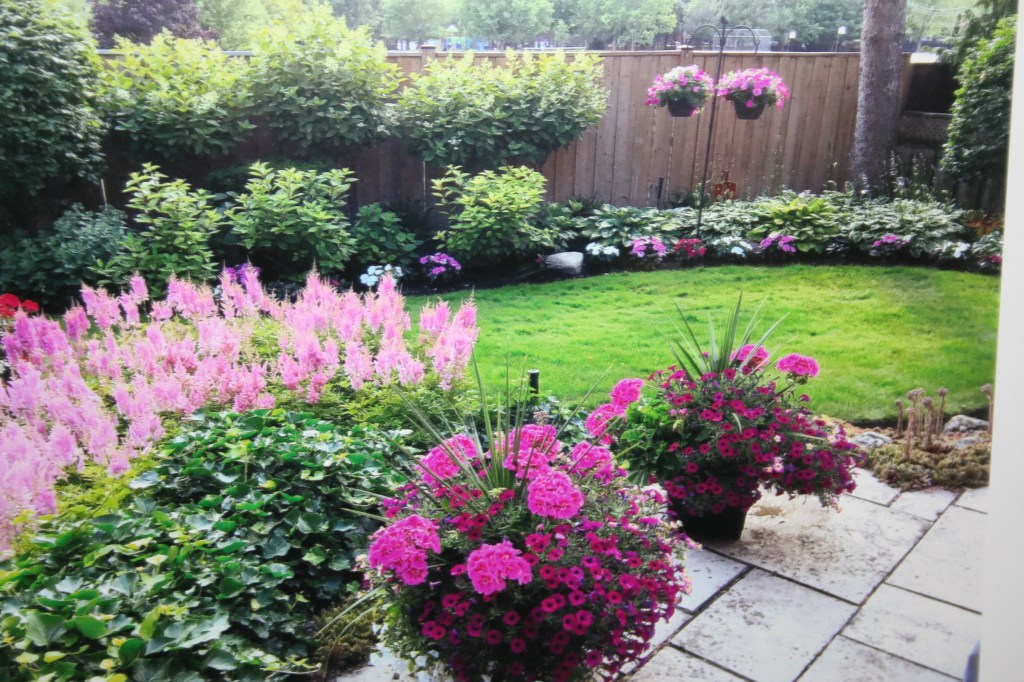 Beautiful garden with pink flowers and bright green alwn