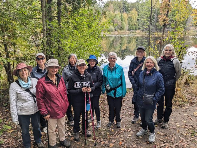 10 ladies in fall wear in front of pond on the Scout Tract