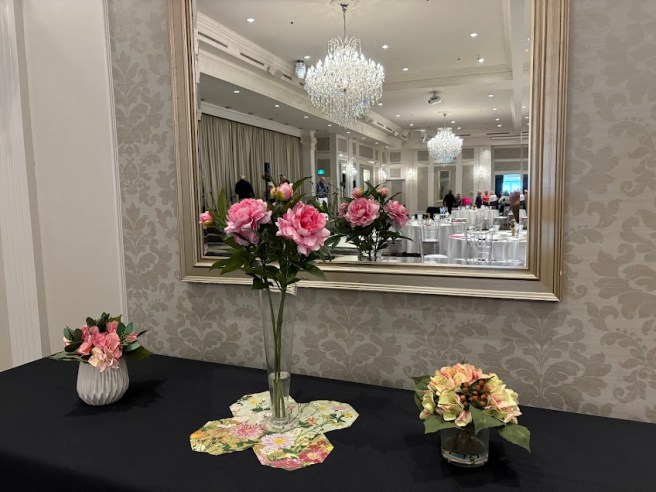 roses and flowers in front of a mirror reflecting the banquet hall